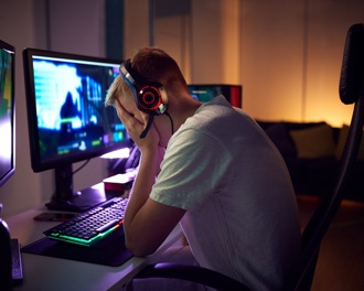 A man sitting at a computer with his head in his heands