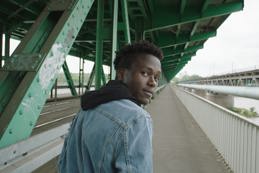 Man looking back whilst walking over a bridge