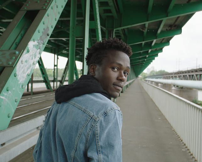 Man looking back whilst walking over a bridge