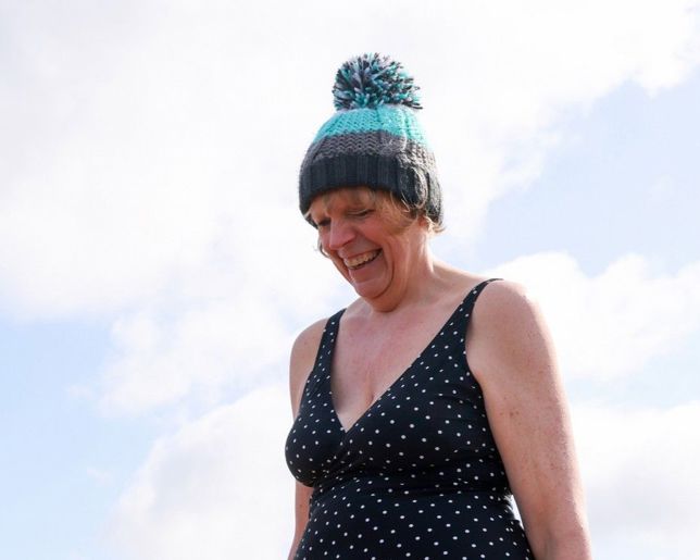 a very happy women wearing a beanie hat and a swimsuit